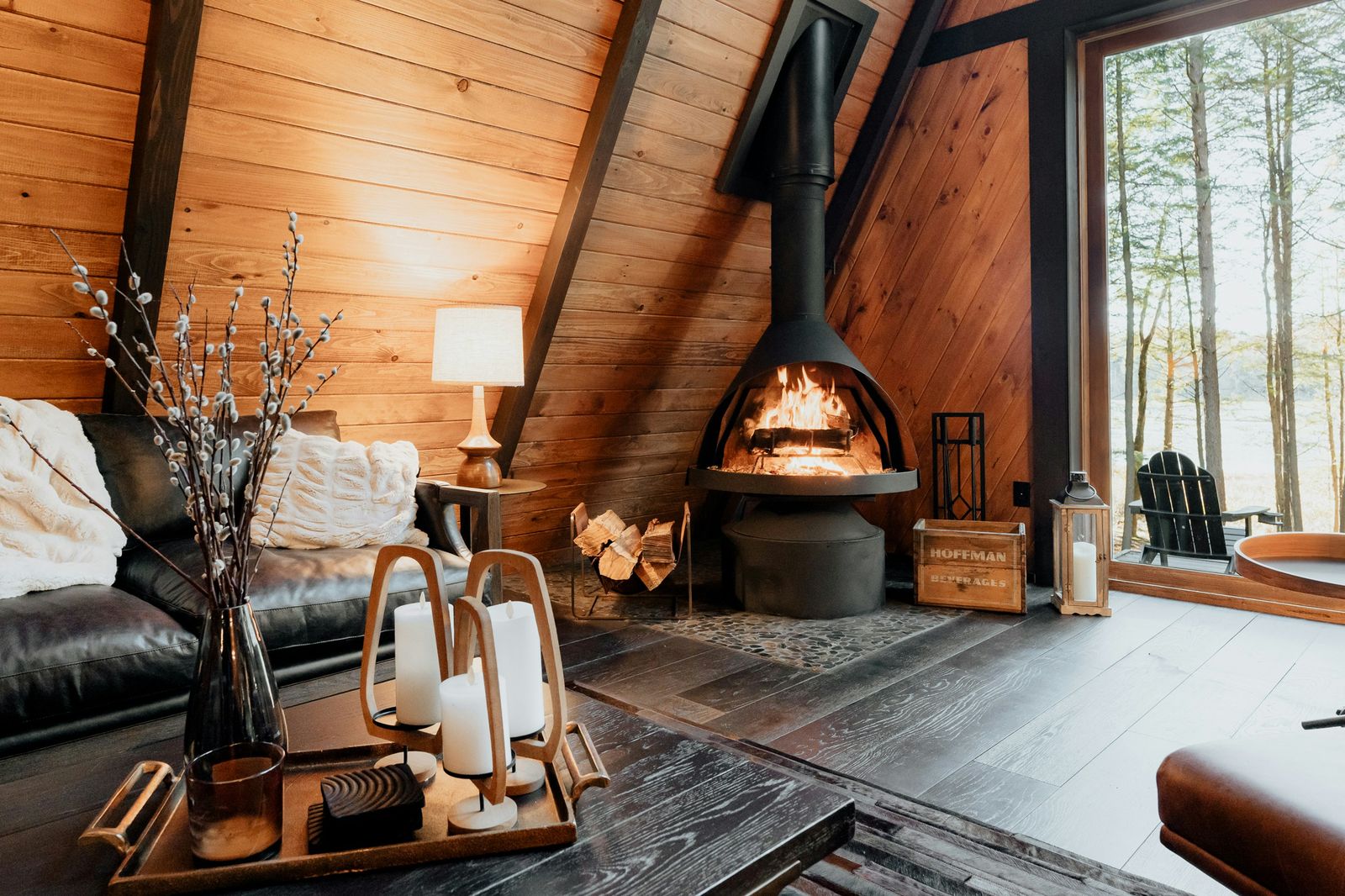 Intérieur de chalet en bois avec cheminée, bougies et vue sur la forêt
